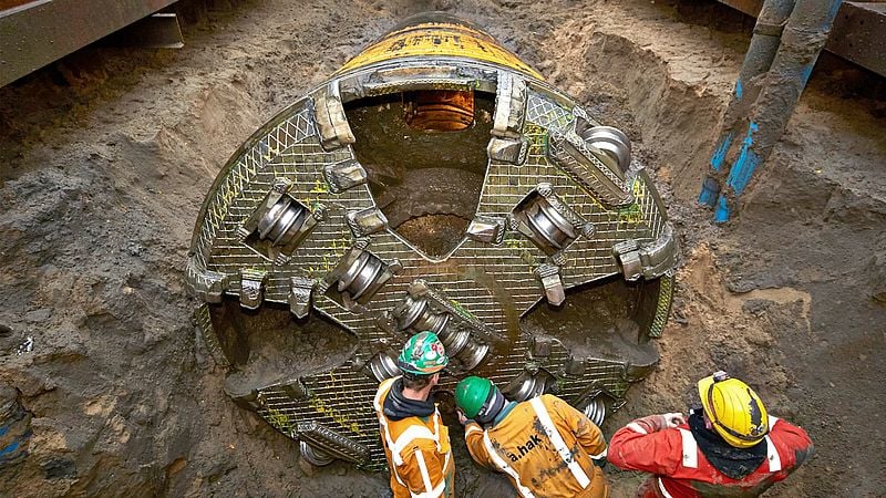 Three construction site employees working on a tunnel boring machine underground