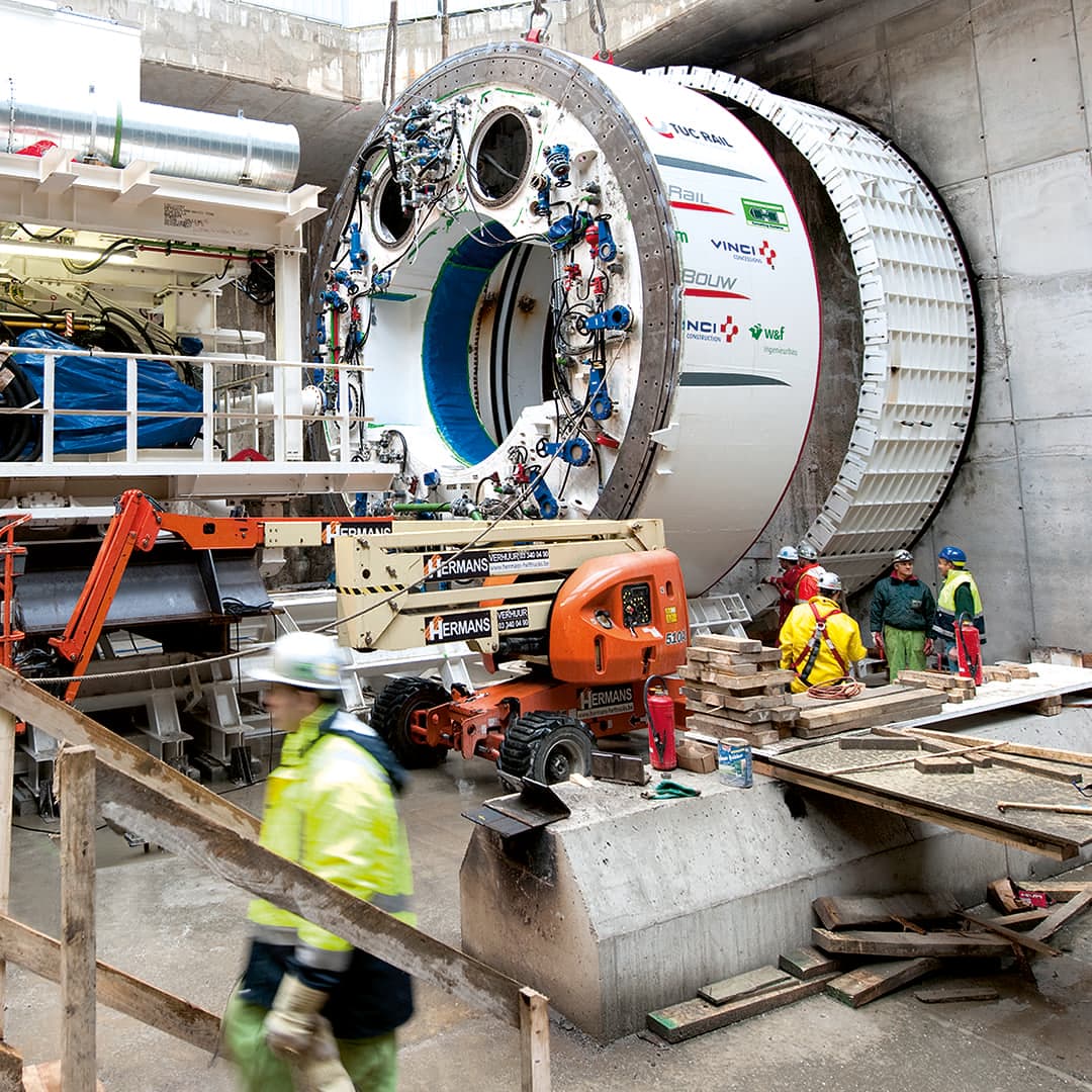 White tunnel boring machine on a construction site with construction site personnel around it.