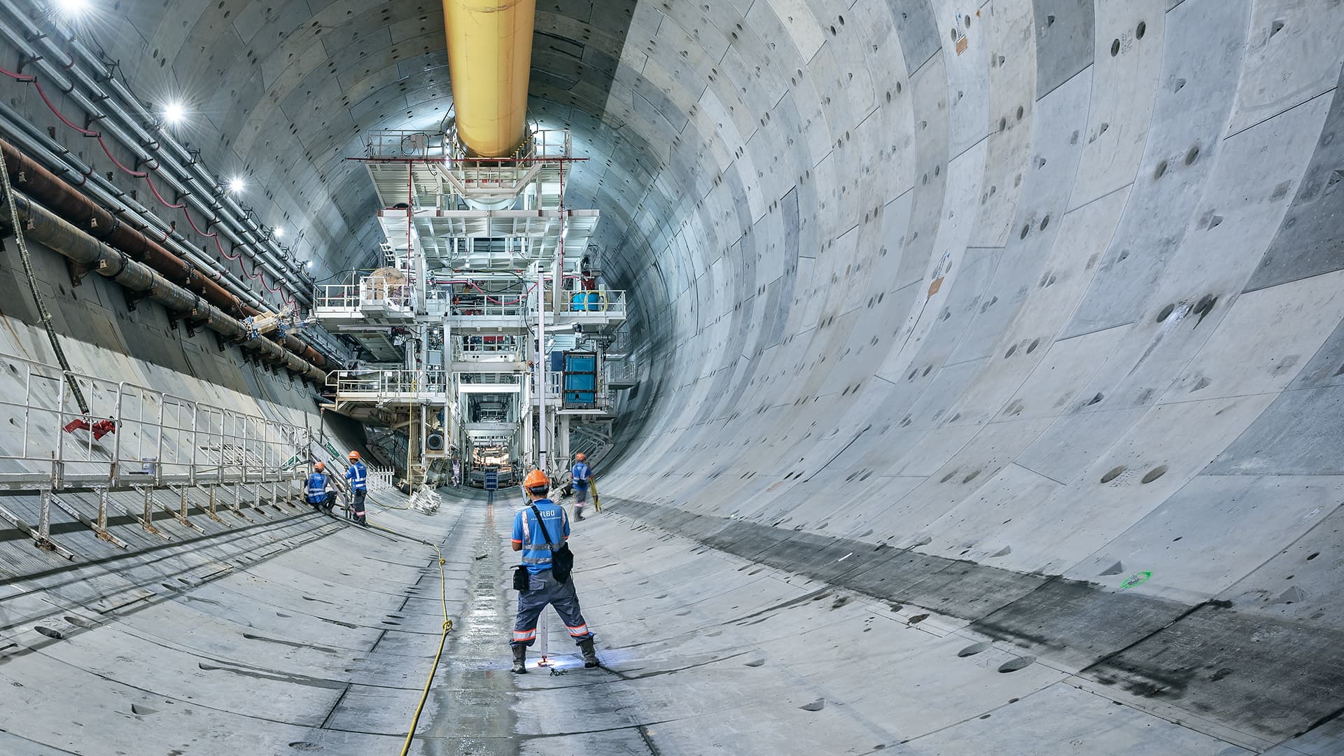 Bild einer mit Tübbinge ausgekleidete Tunnelröhre mit einem Baustellenmitarbeiter 